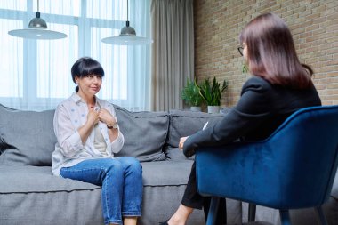 50 'li yaşlardaki olgun bir kadın psikologla terapi seansı yapıyor. Ofiste koltukta oturuyor. Yaşlıların akıl sağlığı, danışmanlık, tedavi, psikolojik yardım, psikoloji psikoterapi konsepti