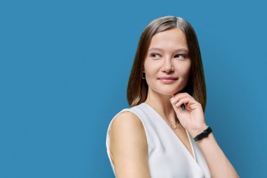 Doğal makyajlı, dudak kirpikleri, mavi stüdyo arka planında saç stili, fotokopi alanı olan çekici bir kadının güzel portresi. Sağlıklı saç, sağlıklı cilt, bakım, kozmetik