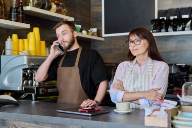 Takım, ortaklar, genç bir erkek ve olgun bir kadın barın arkasında telefonla konuşuyor. Takım, küçük işletme, iş, personel, kafeterya restoranı, girişimcilik konsepti