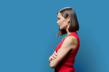 Profil görüntüsü, kırmızı kollu, kendine güvenen, başarılı, ciddi, ciddi bir genç kadın, kopya uzay mavisi stüdyo arkaplan, reklam metni için alan. İş, iş, hizmet, eğitim, insanlar