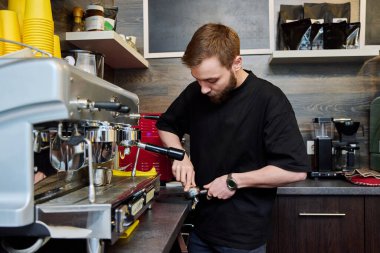 Kahve dükkanında kahve hazırlayan erkek barmen, kahve makinesinin yanında duran önlüklü, sakallı genç adam. Küçük işletme, yemek servisi işi, kahve dükkanı, personel, iş konsepti