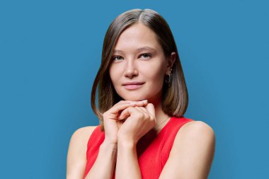 Doğal makyajlı genç bir kadın yüzü, son moda burun delici takılar, mavi arka planda parlak, sağlıklı düz saçlar. Modaya uygun kaşlar kirpikler dudaklar güzel hippi kadınlar. Güzellik moda bakımı