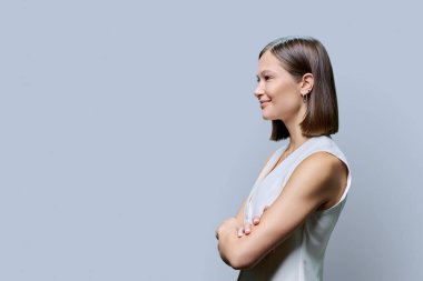 Profil görüntüsü, çapraz kollu başarılı genç iş kadını, kopya uzay gri stüdyo arka planı, reklam metni için alan. İş, iş, hizmet, eğitim, insan kavramı