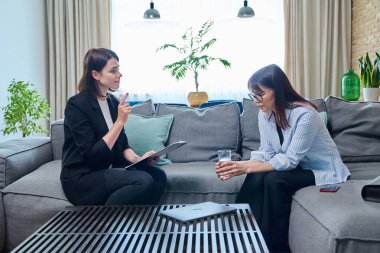 Kadın psikolog, koltukta oturan orta yaşlı kadın hastayla terapi seansı yapıyor. Psikoloji, psikoterapi, terapi, danışmanlık, tedavi, akıl sağlığı konsepti