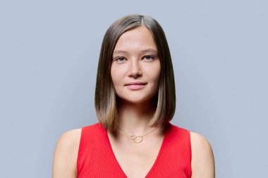 Doğal makyajlı genç bir kadın yüzü, son moda burun delici mücevherler, gri arka planda parlak, sağlıklı düz saçlar. Modaya uygun kaşlar kirpikler dudaklar güzel hippi kadınlar. Güzellik moda bakımı