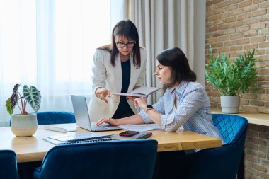 Ofiste konuşan ve tartışan iki iş kadını. Bayan meslektaşlar, yönetici ve çalışanlar belgeleri, sözleşmeleri, mali raporları inceler ve tartışırlar. İş hukuku finansman takım çalışması iş kavramı