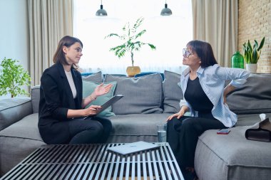 Orta yaşlı kadın psikolog ofisinde terapi seansında. Terapist danışman sosyal hizmet görevlisi 40 'lı yaşlarda not alan kadın hastalarla konuşuyor. Psikoloji psikoterapi tedavisi akıl sağlığı desteği