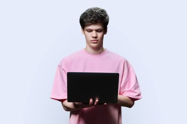 Laptop beyaz stüdyo geçmişi kullanan genç bir üniversite öğrencisi. Kendine güveni olan ciddi bir adam ekrana bakıyor. İnternet teknolojileri, çevrimiçi öğrenim istirahatı, sanal uzaktan eğitim eğlence iletişimi