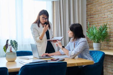 Ofiste konuşan ve tartışan iki iş kadını. Bayan meslektaşlar, yönetici ve çalışanlar belgeleri, sözleşmeleri, mali raporları inceler ve tartışırlar. İş hukuku finansman takım çalışması iş kavramı
