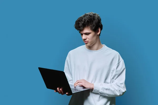 Młody Student Korzystający Laptopa Niebieskie Tło Studio Poważny Pewny Siebie — Zdjęcie stockowe