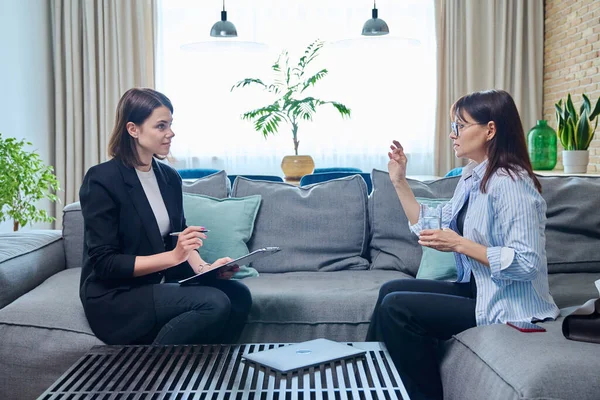 Kadın psikolog, koltukta oturan orta yaşlı kadın hastayla terapi seansı yapıyor. Psikoloji, psikoterapi, terapi, danışmanlık, tedavi, akıl sağlığı konsepti