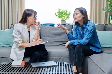 Psikolog ofisinde terapi gören genç bir kadın. Terapist danışman sosyal hizmetler görevlisi 20 'li yaşlarda not alan kadın hastalarla konuşuyor. Psikoloji psikoterapi tedavisi zihinsel sağlık desteği