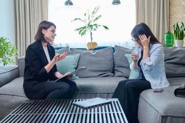 Orta yaşlı bir kadın psikolog danışmanıyla görüşüyor, koltukta oturuyor. Ruhsal sorunları olan bir kadın, psikolojik destek. Psikoloji psikoterapi tedavisi, sağlık hizmetleri.