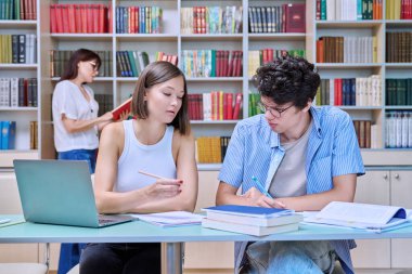 Üniversite öğrencileri kütüphanede ders çalışıyor. Öğrenciler sınava hazırlanıyorlar, bilgisayarda yazıyorlar, okuyorlar ve yazıyorlar. Eğitim, bilgi, öğrenme, gençlik kavramı