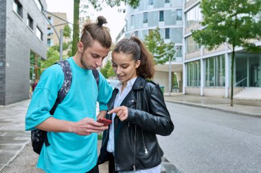 Genç arkadaşlar, ellerinde akıllı telefonlar, şehirde cep telefonları kullanarak ekranlara bakıyorlar. Boş zaman çalışması iletişimi için internet dijital teknoloji uygulamaları