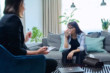 Orta yaşlı kadın psikolog ofisinde terapi seansında. Terapist danışman sosyal hizmet görevlisi 40 'lı yaşlarda not alan kadın hastalarla konuşuyor. Psikoloji psikoterapi tedavisi akıl sağlığı desteği