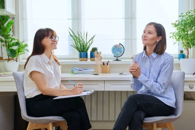 Terapi seansında genç bir kadın terapist ofisinde kadın psikologla konuşuyor. Gülümseyen kadın hasta, profesyonel danışman, psikoterapist, zihinsel sağlık gençliği konsepti