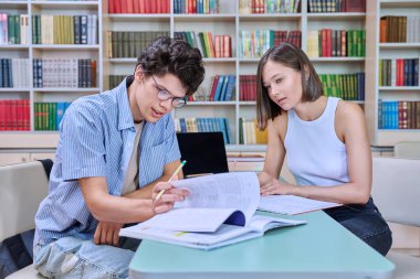 Üniversite öğrencileri kütüphanede ders çalışıyor. Öğrenciler sınava hazırlanıyorlar, bilgisayarda yazıyorlar, okuyorlar ve yazıyorlar. Eğitim, bilgi, öğrenme, gençlik kavramı