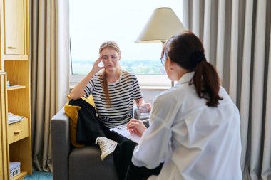 16-17 yaşlarında genç bir kız. Danışman psikolog davranış öğretmeni ile konuşuyor. Görevde oturuyor. Psikoloji psikoterapisi. Akıl sağlığı gençliği.