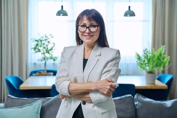 Portrait of business elegant middle-aged woman in home office. Confident successful female with crossed arms looking at camera. Job service leadership career control management administration people