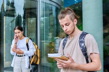 Genç hippi, 18 yaşında, 19 yaşında, sırt çantalı, açık havada duran defterleri var, eğitim amaçlı bina geçmişi var. Gençlik, eğitim, yaşam tarzı konsepti