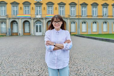 Kendine güvenen orta yaşlı kadın öğretmen, akıl hocası, kollarını kavuşturmuş poz veren pedagog. Eğitim binası, üniversite üniversitesi.