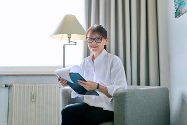 Ofis sandalyesinde oturan orta yaşlı bir kadının portresi. Olgun, dost canlısı, profesyonel, psikolog psikoterapist, sosyal hizmet görevlisi, iş yeri danışmanı.