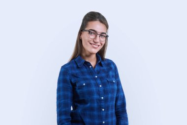 Beyaz stüdyo arka planında dişleri olan gülümseyen genç bir kadının portresi. 30 yaşında, gözlüklü, sıradan gömlekli bir kadın. Gençlik, yaşam tarzı, insan konsepti