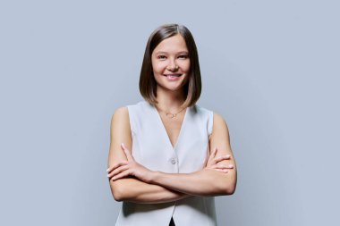 Gri stüdyo arka planında kameraya bakan kollarını çapraz bağlamış, kendine güvenen, ciddi bir kadın. Güzellik, iş, iş... Girişimcilik... İşletme uzmanlığı...