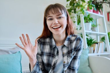 Web kamerasında 19-20 yaşlarındaki genç bir kızın kameraya, internet toplantısına ve sohbet konferansına baktığı görülüyor. Genç trend hipster kadın blogger vlog kaydedici ev içi video