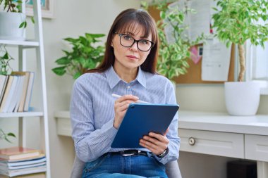 Ofiste dijital tabletle oturmuş kameraya bakan kadın psikolog sosyal hizmet uzmanı portresi. Psikoloji psikoterapisi yardımcı oluyor.