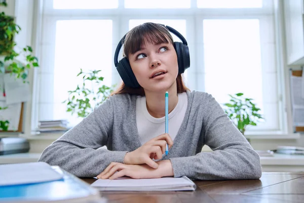 stock image Web camera view of teenage student girl in headphones looking at camera sitting at desk with textbooks notebooks. Online lesson video chat call conference. Technology education training e-learning