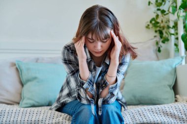 Evdeki kanepede oturan üzgün, yalnız genç kadın. Hayal kırıklığına uğramış 19-20 yaşlarında, kederli bir üniversite öğrencisi. Depresyon, stres, zihinsel zorluklar, gençlik kavramı