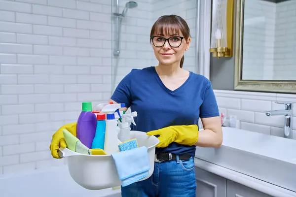 中年妇女戴手套 浴室里有一盆洗涤剂 准备日常打扫房屋的女性 在工作场所摆姿势的家政服务人员 料理家务的概念 — 图库照片