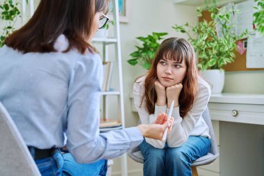 Ruh sağlığı uzmanı, psikolog, danışman ve sosyal hizmet görevlisinin ofisinde toplanan üzgün, ciddi bir genç kız. Duygular, güçlükler, sorunlar, depresyon, stres, gençlik kavramı