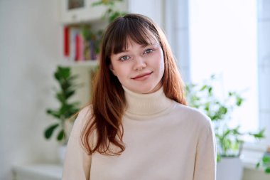 Gülümseyen güzel bir genç kızın portresi. 18-20 yaşlarında. Burnunda piercing olan modern üniversite öğrencisi kameraya bakıyor. Gençlik, güzellik, moda, yaşam tarzı konsepti