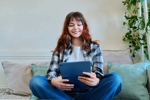 コミュニケーションレジャーのフリーランスを勉強するためのデジタルタブレットを使用して 若い魅力的なトレンディな女子大学の学生は 自宅でソファーに座っています テクノロジー ライフスタイルコンセプト — ストック写真