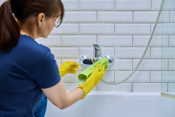 洗剤のスプレーおよび専門のラグが付いている洗浄の浴室 洗浄蛇口 タイル 泡のクリーナーを掃除する女性 ハウスキーピング ハウスワーク クリーニング クリーニングサービスのコンセプト — ストック写真