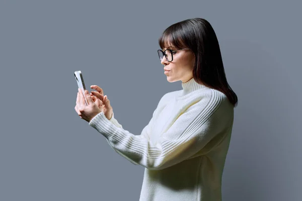 Profilo Vista Mezza Età Donna Seria Utilizzando Smartphone Sfondo Grigio — Foto Stock