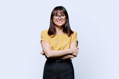 Beyaz stüdyo arka planında kollarını kavuşturmuş kendine güvenen olgun bir kadının portresi. Başarılı, mutlu, orta yaşlı kadın kameraya bakıyor. İş, iş, yaşam tarzı, 40 'lı yaşlarda insanlar