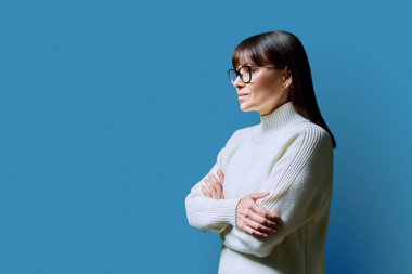 Orta yaşlı mutlu kadının profil görüntüsü ileriye bakan, mavi stüdyo arka planı, reklam metni için kopya alanı. Olgun iş, kendine güvenen başarılı kadın. Pazarlama satış hizmetleri, insanlar