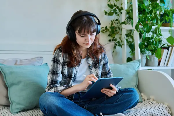 Dijital tabletli genç bir bayan. Stylus evde kanepede otururken resim çiziyor. Teknolojiler, eğlence, yaratıcılık, eğitim, serbest çalışma, yaşam tarzı, gençlik kavramı