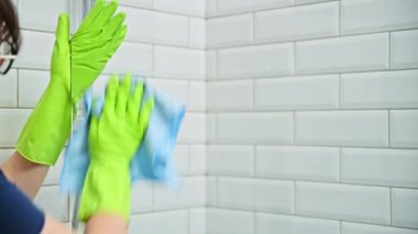 Eldivenli kadın banyoyu temizliyor, duşta bardağı yıkıyor, profesyonel cam bezle yıkıyor. Oda servisi, ev işi, ev temizliği, temizlik hizmeti konsepti.
