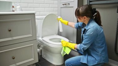 Koruyucu eldivenlerle temizlik yapan kadın temizlikçi deterjan profesyonel bez kullanarak tuvaleti temizliyor. Hijyen, dezenfeksiyon, temizlik, ev işi, ev temizliği.