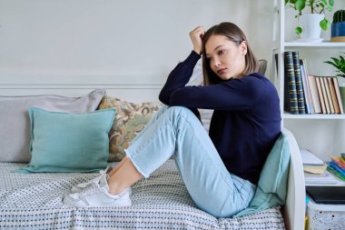 Evdeki kanepede oturan üzgün mutsuz genç kadın. Hayal kırıklığına uğramış, kafası karışmış bir kadın, zorluklar yaşıyor. Zihinsel sorunlar, duygular, yalnızlık, stres, depresyon, güçlükler, gençlik kavramı