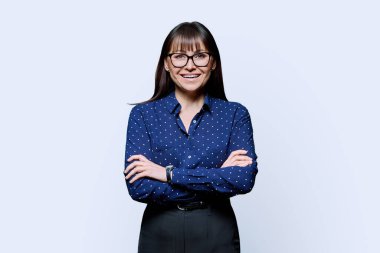 Beyaz stüdyo arka planında kollarını kavuşturmuş kendine güvenen olgun bir kadının portresi. Başarılı, mutlu, orta yaşlı kadın kameraya bakıyor. İş, iş, yaşam tarzı, 40 'lı yaşlarda insanlar