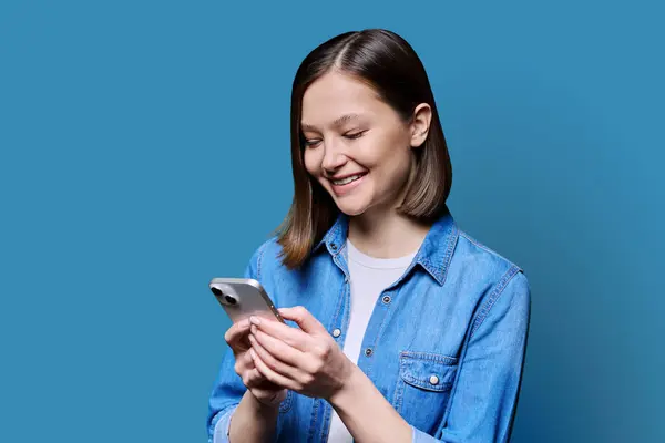 Jovem Mulher Feliz Usando Smartphone Fundo Azul Vinte Poucos Sorrisos — Fotografia de Stock