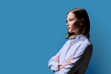 Profil bakış açısı, kendine güvenen başarılı, kollarını kavuşturmuş genç iş kadını, kopya uzay mavisi stüdyo arka planı, reklam metni için alan. İş işleri hizmetleri eğitim insanları kavramı