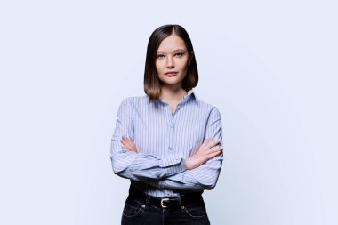 Beyaz stüdyo geçmişinde çapraz kollu, kendinden emin, ciddi bir kadın. Gömlekli bir iş kadını, kameraya bakan bir girişimci öğrenci. İş, iş, eğitim, insan kavramı