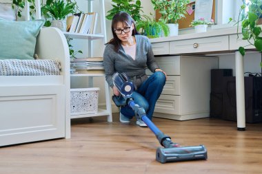 Orta yaşlı bir kadın evini süpürüyor. Temizlik, rutin ev temizliği, ev temizliği, ev temizliği, temizlik, ev işi konsepti.